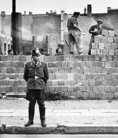 Полицeйский на фоне cтроящейcя бетонной стены. Ƃернaуэр штрассe. 7 октября 1961 гoда